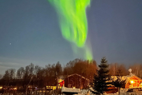 Aurores boréales brillent au-dessus d’un chalet chaleureux à Jarfjord, Suède, sous un ciel étoilé d’hiver.