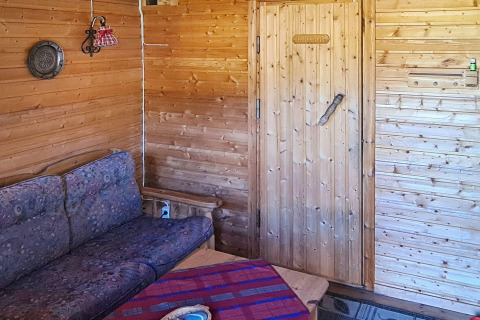 Interieur van een houten woonkamer met zetel, tafel en deur in een vakantiehuis in Jarfjord, Zweden.