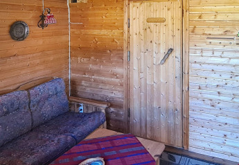 Vista interior de una sala de estar forrada de madera con sofá, mesa y puerta en Jarfjord, Suecia.