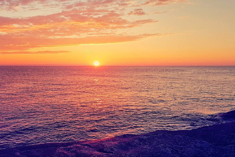 Coucher de soleil sur la mer depuis un chalet à Jarfjord, Suède, avec des nuages colorés et mer paisible.
