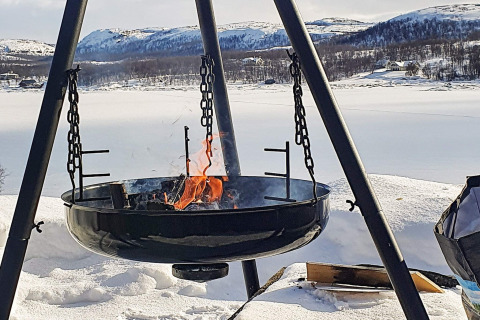 Feuerschale auf Terrasse eines Chalets mit Schneelandschaft und Bergen in Jarfjord, Schweden.