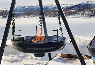Fogón exterior en chalet para 7 personas en Jarfjord, Suecia, con vista a montañas y lago nevado.