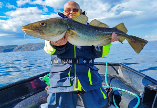 Man houdt grote kabeljauw op boot bij het 7-persoons vakantiehuis in Jarfjord, Zweden, op het water.