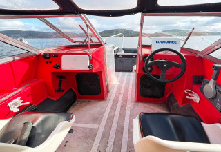 Innenraum eines roten Motorboots mit Steuerstand und Blick auf das Wasser bei Jarfjord, Schweden.