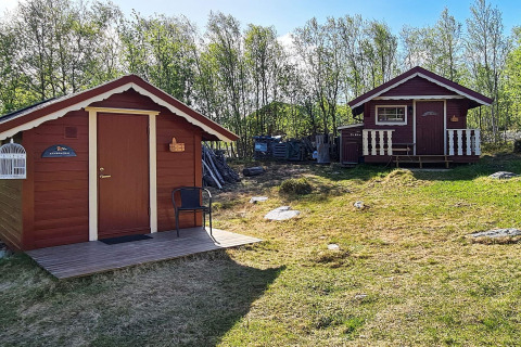Twee rode houten huisjes in een groene omgeving bij het vakantiehuis in Jarfjord, Zweden.