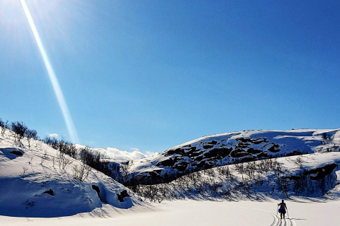 Skifahrer in verschneiter Landschaft unter blauem Himmel bei der Hütte '7 person holiday home in JARFJORD', Schweden.