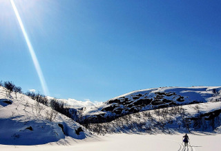Person på ski i sneklædt dal under klar blå himmel nær chalet '7 person holiday home in JARFJORD', Sverige.