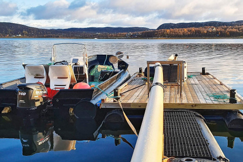 Boot met Suzuki-motor aan houten steiger vanuit vakantiehuis in Jarfjord, Zweden bij rustig water.