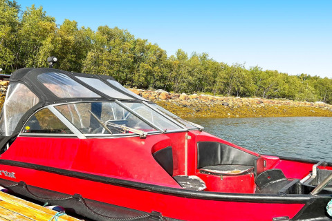 Rotes Motorboot am Steg mit bewaldeter Küste und Felsen im Hintergrund, aufgenommen am Jarfjord.