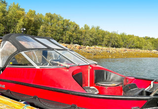 Rode motorboot aan de steiger met rotsachtige oever en bomen, genomen bij het vakantiehuis in Jarfjord.