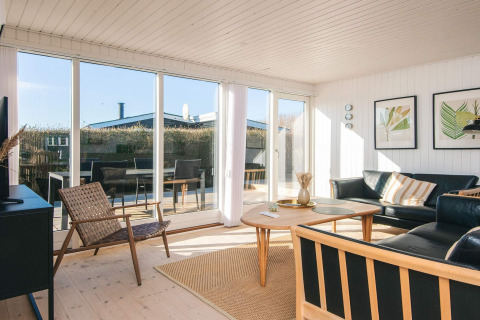 Helles Wohnzimmer im 'Renovated Beach House' in Dänemark mit großen Fenstern und moderner Einrichtung.