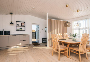 Casa de playa renovada en Dinamarca con cocina luminosa, mesa de comedor de madera y mucha luz natural.
