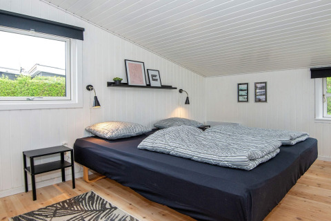 Soveværelse i 'Renovated Beach House' i Danmark med sort seng, hvide vægge og moderne dekoration.