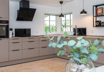 Cocina moderna en el Renovated Beach House de Dinamarca con muebles claros, ventanas grandes y toques de madera.