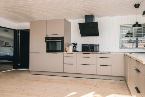 Cucina moderna nella Renovated Beach House in Danimarca, con mobili beige e design elegante.