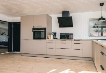 Cucina moderna nella Renovated Beach House in Danimarca, con mobili beige e design elegante.