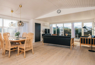 Lyst, moderne opholdsområde i det renoverede strandhus i Danmark med træmøbler og store vinduer.