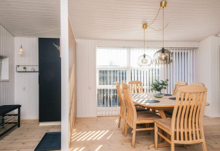 Comedor en la Renovated Beach House en Dinamarca con muebles de madera clara y grandes ventanales.