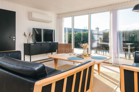Modern ingerichte leefruimte in het Renovated Beach House in Denemarken met grote ramen en terraszichten.