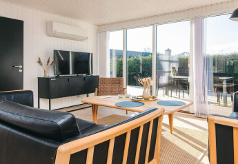 Acogedora sala de estar en Renovated Beach House en Dinamarca con ventanales y muebles modernos de madera.