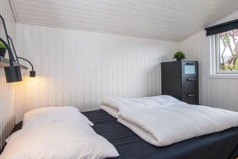 Slaapkamer in het Renovated Beach House met witte wanden, tweepersoonsbed en zwarte ladekast.