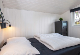 Soveværelse med sort kommode, stort vindue, hvidmalede vægge og dobbeltseng i Renovated Beach House.