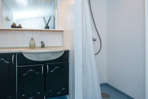 Badkamer in het vernieuwde strandhuis in Denemarken met zwarte wastafel, douche en spiegel.