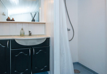 Badkamer in het vernieuwde strandhuis in Denemarken met zwarte wastafel, douche en spiegel.