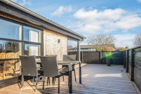 Zonnig houten terras met zwarte tuinmeubels bij het Renovated Beach House in Denemarken.