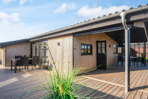 Casa sulla spiaggia ristrutturata in Danimarca con terrazza in legno, zona pranzo esterna e rivestimento moderno.