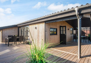 Maison de plage rénovée au Danemark avec terrasse en bois, coin repas extérieur et façade en bois moderne.