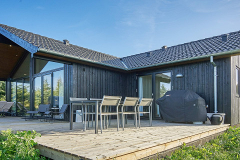 Terrasse extérieure d’une maison de vacances 8 personnes à Aakirkeby, Danemark, avec table, chaises et barbecue.