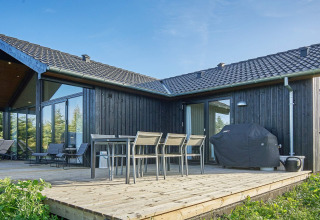 Terrasse extérieure d’une maison de vacances 8 personnes à Aakirkeby, Danemark, avec table, chaises et barbecue.