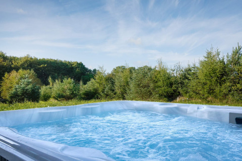 Bubbelend buitenjacuzzi met zicht op bos bij 8-persoons vakantiehuis in Aakirkeby, Denemarken.