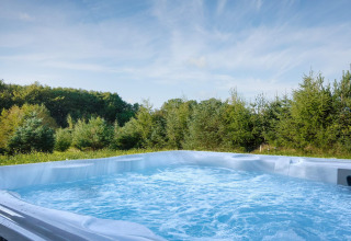 Jacuzzi extérieur à bulles devant une forêt, au gîte pour 8 personnes à Aakirkeby, Danemark.