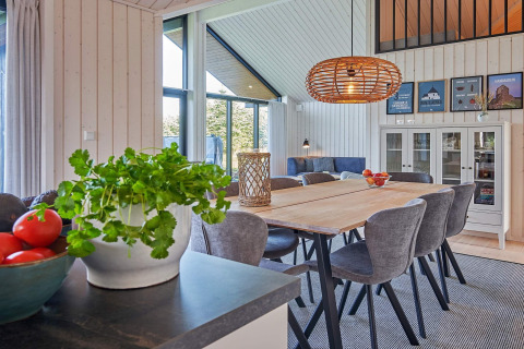 Luminoso y moderno comedor de casa vacacional para 8 personas en Aakirkeby, Dinamarca, con vistas verdes.