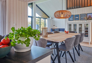 Salle à manger moderne et lumineuse dans une maison de vacances pour 8 à Aakirkeby, Danemark, avec vue nature.