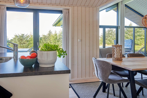 Luminoso angolo cucina e sala da pranzo in casa vacanze per 8 persone ad Aakirkeby, Danimarca, vista verde.