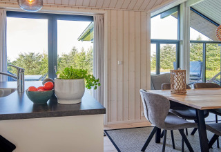 Cuisine moderne et salle à manger lumineuses dans un gîte 8 personnes à Aakirkeby, Danemark, vue verdoyante.