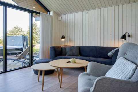 Acogedora sala de estar en casa de vacaciones en Aakirkeby, Dinamarca, con ventanales y terraza exterior.