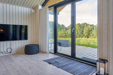 Salón moderno con grandes puertas de cristal, terraza y vista natural, casa vacacional en Aakirkeby, Dinamarca.