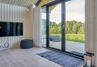 Salón moderno con grandes puertas de cristal, terraza y vista natural, casa vacacional en Aakirkeby, Dinamarca.