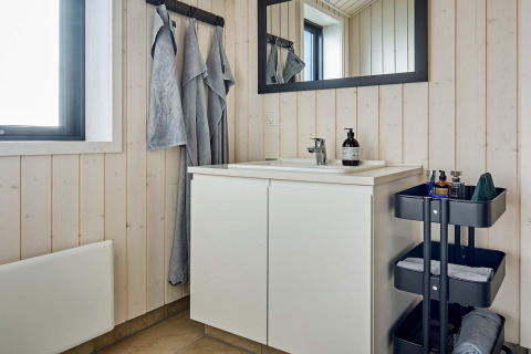 Moderne badkamer met witte wastafel, spiegel en handdoeken in een vakantiewoning in Aakirkeby, Denemarken.