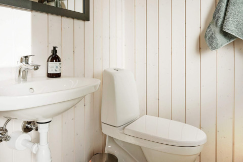 Badezimmer mit Waschbecken, weißer Toilette und Handtuch im 8-Personen-Ferienhaus in Aakirkeby, Dänemark.