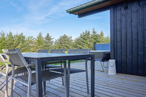 Udendørs terrasse ved 8 personers feriehus i Aakirkeby, Danmark med spisebord, stole og jacuzzi