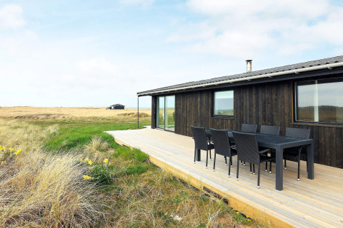 Casa vacanze moderna a Hjørring, Danimarca, terrazza in legno, area pranzo esterna e vista sulla natura.