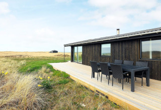 Modern vakantiehuis in Hjørring, Denemarken met houten terras, eettafel buiten en ruim uitzicht.