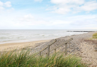 View of the beach from the dunes near ‘7 person holiday home in Hjørring’, Denmark, with stairs and sea.