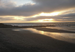 Solnedgang over stranden ved feriehuset '7 person holiday home in Hjørring' i Danmark med bløde skyer.