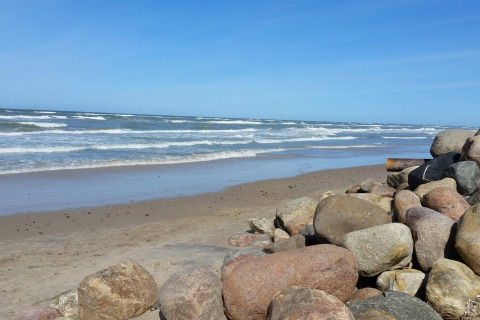 Kystbillede fra stranden ved 7 personers feriehus i Hjørring, Danmark, med klipper og bølger.